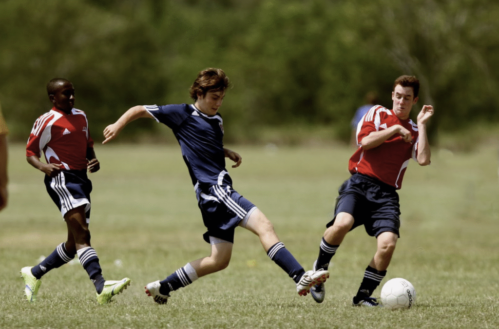Football players training on field with coach demonstrating proper techniques and skills development