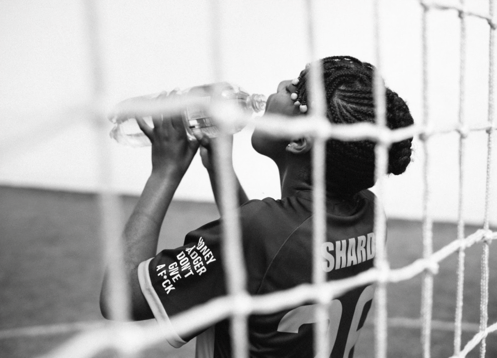 African American female goalkeeper drinking water during football training break for proper hydration
