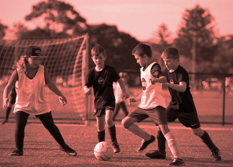 Youth soccer players practicing passing, shooting and heading skills during training session